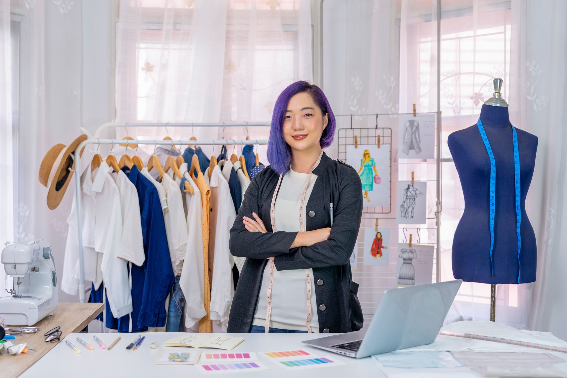 young cool asian female designer with purple hair standing with arms crossed in her studio,fashion stylist at work in workshop